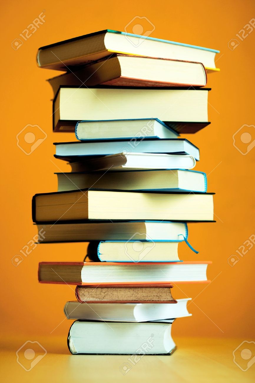 866x1300 Stack Of Books Resembling A Pillar On A Table Before Orange Wall